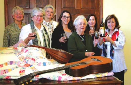 Festival Hill Gala Planning Committee doing a tasting from Majek Winery. A selection of auction items in the front. The quilt is donated from James Dick and belonged to his first piano teacher Leota Anderson. Pictured are (from left) Judy Hancock, Pat Johnson, Pat McMahen, Susannah Mikulin, Joanie Havlick, Sandy Millyer and Co-Chair Katrina Elvig.