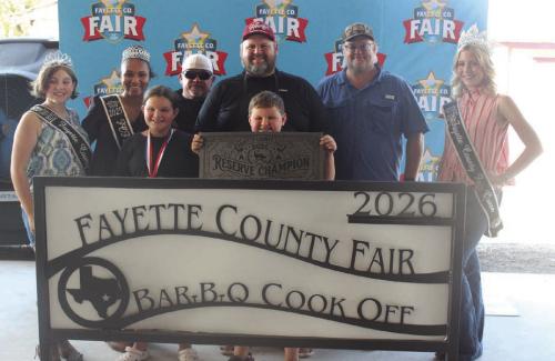 The team of Good and Ready won reserve champion and first place pork butt at Saturday’s Fayette County Fair Bar-B-Q Cook Off. Left to right, 2025 Jr. Miss Fayette County Anabelle Zwahr, 2025 Queen second runner-up Keanna Henderson, Lillian Tofel, Tiger Hall, head cook David Tofel, Frank Tofel (holding banner), Michael Tofel and 2025 Fair Queen Hailey Janish.