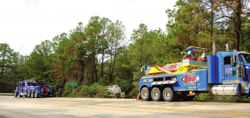 Two heavy duty tow trucks worked together to pull an oilfield tanker out of the pine trees Monday morning. The truck slid off the road after driving across a patch of ice Sunday afternoon. Photo by Andy Behlen