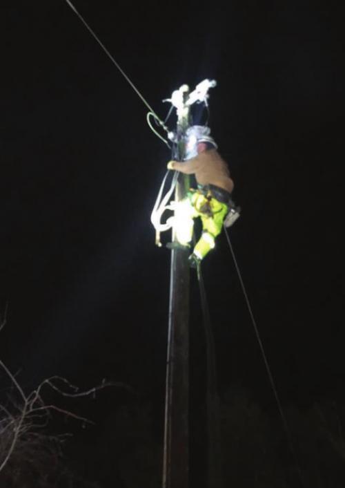 Apprentice Lineman Joey Jasek climbing a pole during the night to pull wire to complete repairs on a downed power line north of Weimar. (Photo credit: Line Foreman Greg Noak)