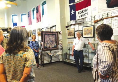Docent Charles Murray explains the signifi cance of wall items to Fayette County Retired Teachers.