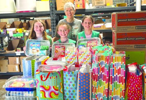 Each Girl Scout troop in Fayette County prepared birthday boxes with all the fixings for a cake and other surprises. On Monday, representatives of Troop 32077 delivered the donations, along with several cases of Girl Scout cookies from their sale stock, to AMEN Food Pantry. Three troop members are shown with Susan Schultz of AMEN.