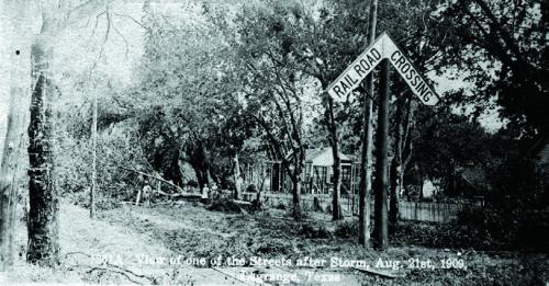 Postcard with caption, “View of one of the Streets after Storm, Aug. 21st, 1909, La Grange, Texas,” shows a family outside a home where the siding had been ripped off. Courtesy of the Fayette Heritage Museum and Archives, La Grange.