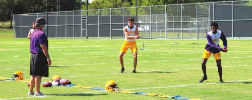 Masked La Grange football coach Matt Kates works Monday with Caden Cooper and Matthew Johnson, returnees, who split time at quarterback last season.