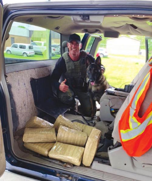 Sgt. Randy Thumann and K9 Kolt with the eight bundles of marijuana found during the traffic stop.