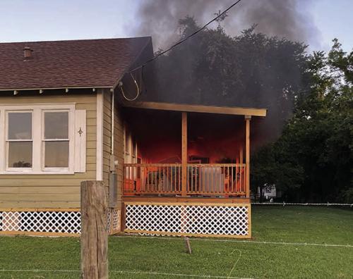 La Grange Police Officer Noah Geer with the help of local pastor Will Martin put out this porch fire with a water hose last Friday.