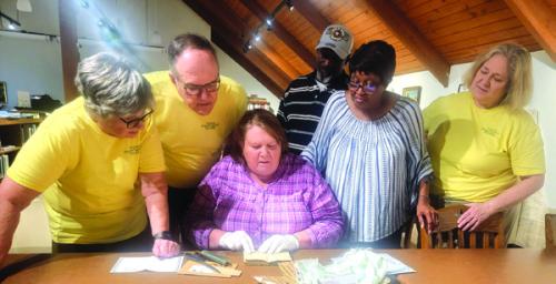 Picture: Members of the Faison Preservation Society watch as library Curator, Rox Ann Johnson, examines the Faison ledger. From left: Marie Watts, Greg Walker, John Willett, Jan Dockery, and Katy Beauford.