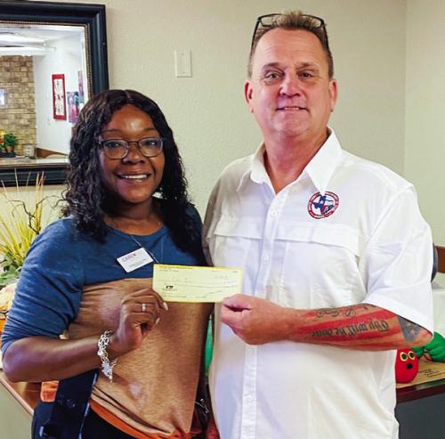 Fayette County Republican Party Chairman Michael P. Schlabach (right) hands a $400 donation sponsor check to Care Inn Head Administrator Chandra Polk (left). The money was used for food and fun on Halloween night so the residents can eat a special meal and hand out candy to Trick or Treaters visiting them that evening.