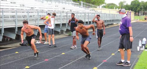A masked coach James Magness, right, oversees agility drills by La Grange athletes on the track Tuesday morning.