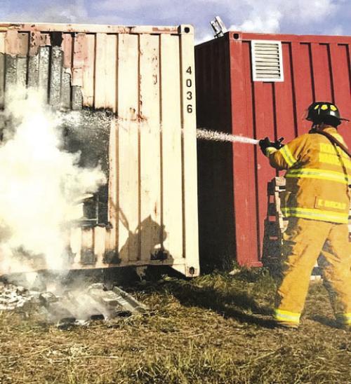 Firefighters extinguish the fire in the storage container.