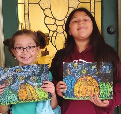 Two proud, young artists show their artwork created in the ARTS Art After School Program.