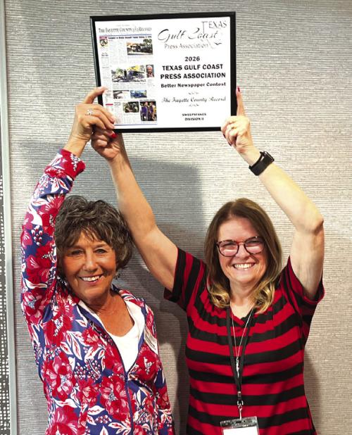 Record owners Nonnie Barton, left, and Regina Keilers, right, hold aloft the Sweepstakes trophy after The Fayette County Record was crowned the top large circulation newspaper by The Texas Gulf Coast Press Association at their annual convention in Port Lavaca Saturday.