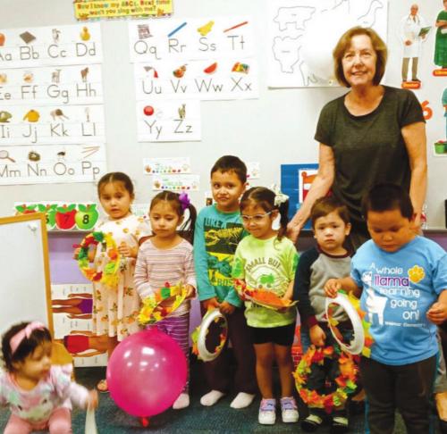 Juanita and the children from the Learn and Play room show the fall wreath they made during the art session.