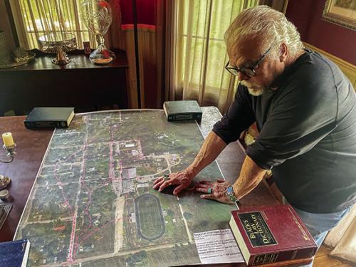 Jay Kirtley of Flatonia stands over a large topographical map of the Flatonia ISD campus and surrounding neighborhoods. Kirtley alleges that the school’s construction projects in recent years have led to an increase in stormwater runoff onto his and his neighbors’ property. Photo by Andy Behlen