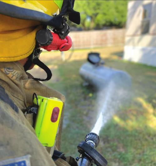 A Flatonia firefighter cools down a propane tank whose relief valve popped open by the heat Monday.