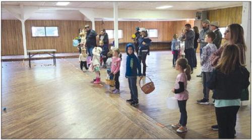 A group of children, with their parents and grandparents, wait patiently to pick up Easter eggs on the Carmine Hall dance floor. The egg hunt was moved to the hall due to the creek and wet grounds at the Carmine City Park.