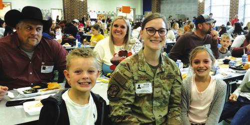 La Grange second grader Dawson Canada and third grader Ally Canada sit on either side of their sister Kaitlin Canada, Airman First Class, when she surprised them at school for lunch last week. Behind them are parents Wes and Brittany Canada.