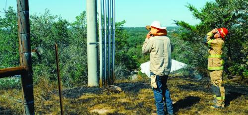 La Grange Firefighter Mike Proske and a lineman from Fayette Electric Cooperative inspect the power pole where the fire started. The electrocuted buzzard can be seen at the base of the pole. Photo by Andy Behlen