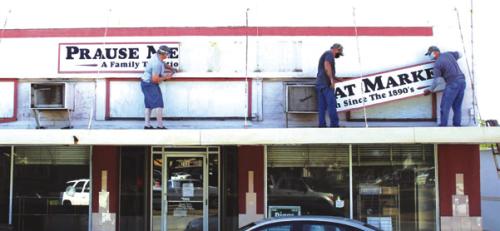 Members of the Prause family take down their exterior sign after they sold the business and building in August 2020. But it never reopened and is now being bought by the city to turn into a theatre. Record File Photo