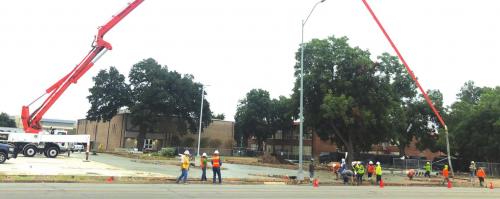 This crew was pouring concrete via a Gateway Arch of sorts Tuesday morning in a parking lot at the La Grange school campus along Travis Street. Photo by Regina Keilers
