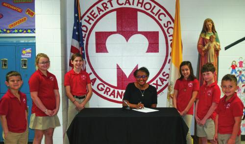 La Grange Mayor Jan Dockery signs Catholic Schools Week Proclamation. The theme for 2022 is “Catholic Schools: Faith. Excellence. Service.” Also pictured are Sacred Heart students, left to right: Cade Harbers, Fallon Wallace, Makenna Emmel, Mayor Jan Dockery, Leah Gulash, Leighton Peschke, Bowen Bishop. Staff photo by Amanda Gifford