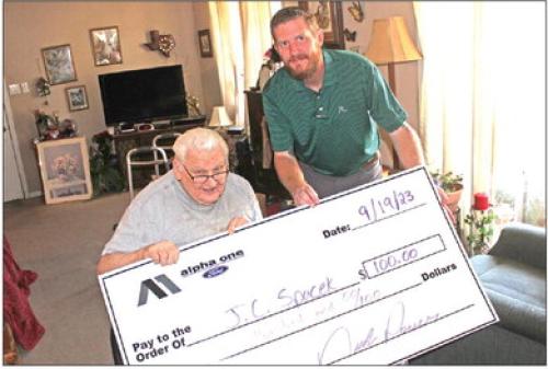 J.C. Spacek of La Grange, above left, seated, is shown here collecting his $100 prize from Nick Power of Alpha One Ford after winning last week’s newspaper reader football pick it contest. Spacek turned in one of eight perfect 10-for-10 ballots last week. His score prediction tiebreaker of the Cowboys game vaulted him to the win. The ballot is included in every Tuesday edition of The Fayette County Record. The contest is sponsored by Alpha One.