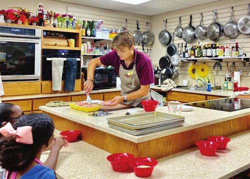 Instructor Coy Heinrich teaches youngsters how to cook at Le Petite Gourmet Shoppe’s Kids ‘N The Kitchen classes, which take place throughout the summer.