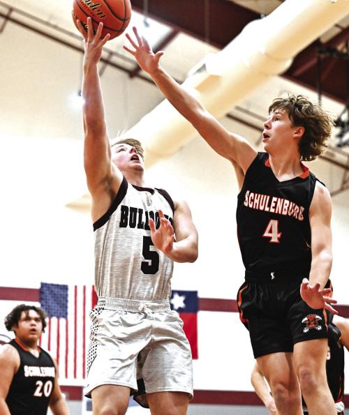 Flatonia’s Dayton Cliffe goes up for two for the Bulldogs against the defense of Schulenburg’s Aaron Janacek Friday. Photo by Stephanie Steinhauser