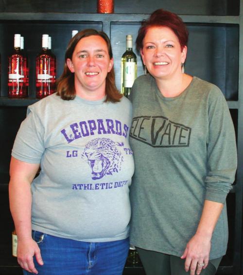 Kristen Denham, left, and Becky Carson, right, stand in front of Bodega’s wine wall. Not pictured are Tiffany Denham and Gene Carson. Photo by Amanda Gifford