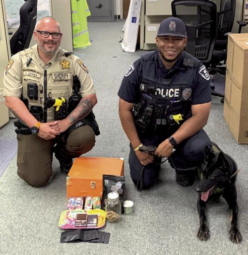 Deputy Josh Jones, Officer Byron Powe, and K9 Semper pictured with the marijuana, vape pens containing THC oil, mushrooms, scales, packaging material and drug paraphernalia recovered during search of the vehicle.