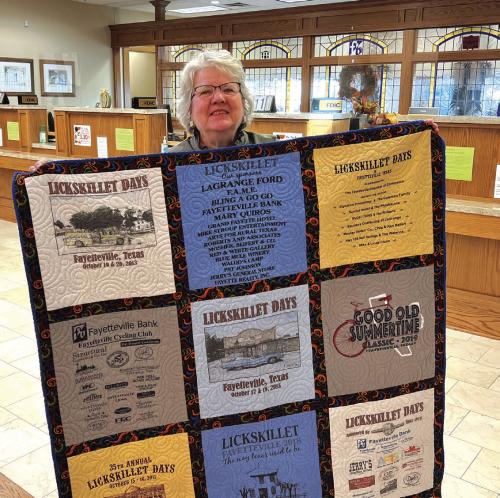 Fayetteville artist, Pat Johnson with the Lickskillet T-shirt quilt. She has been responsible for the art used in the t-shirt designs for over 40 years.